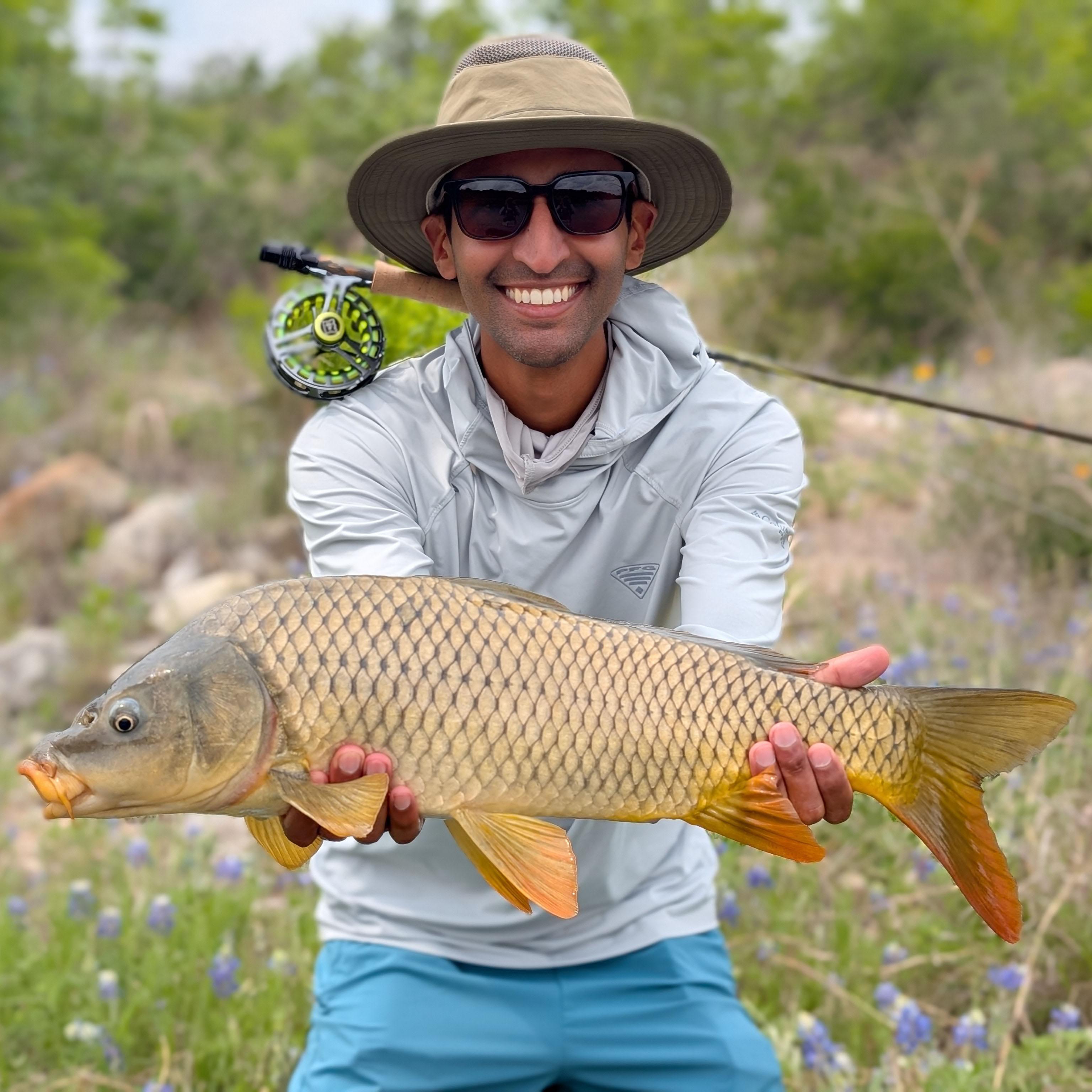 Rehman holding a common carp in front of Texas wildflowers.